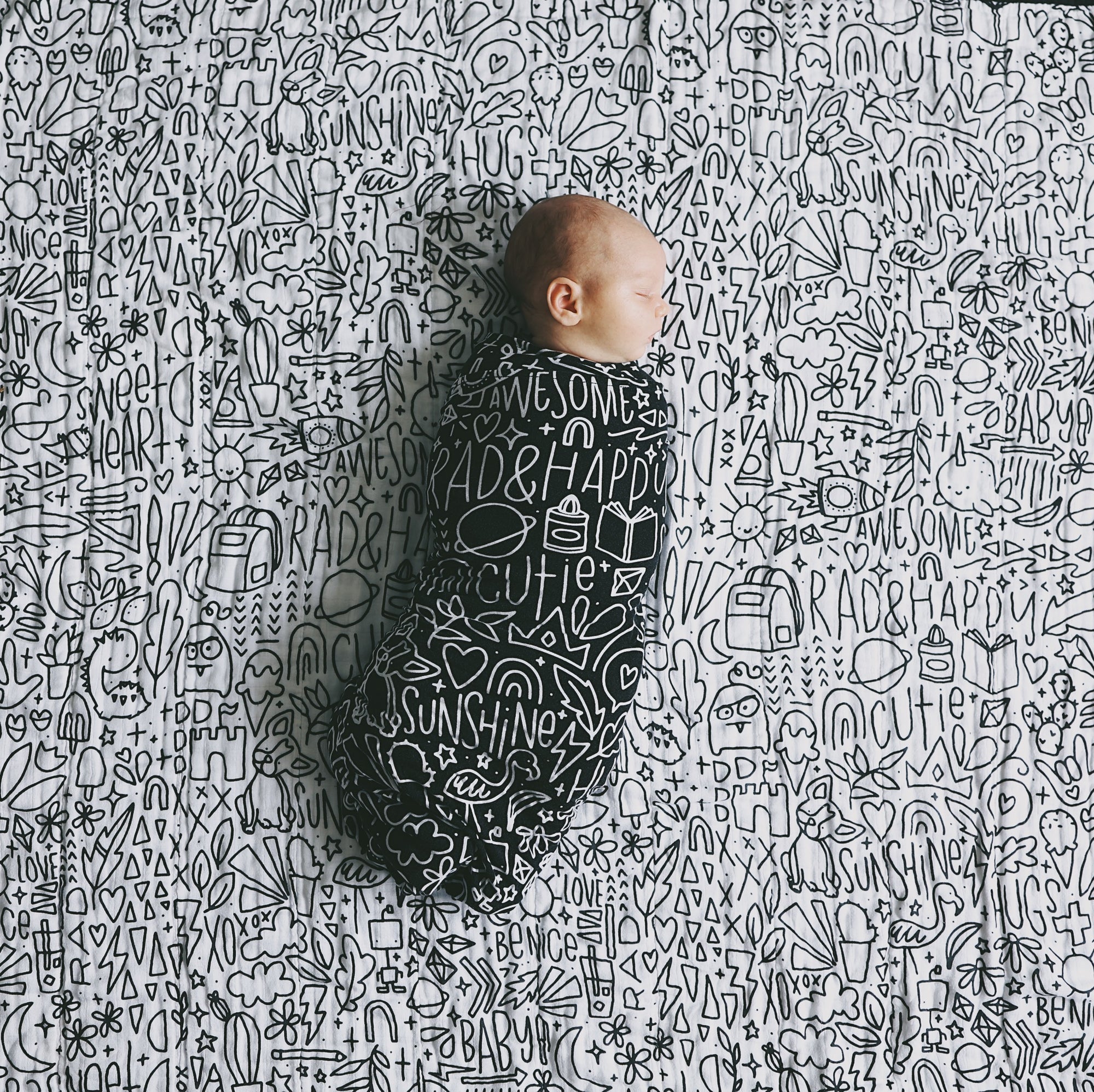 A baby swaddled laying on top of the quilt spread out