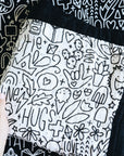 A hand holding the quilt folded in a square on a doodled background