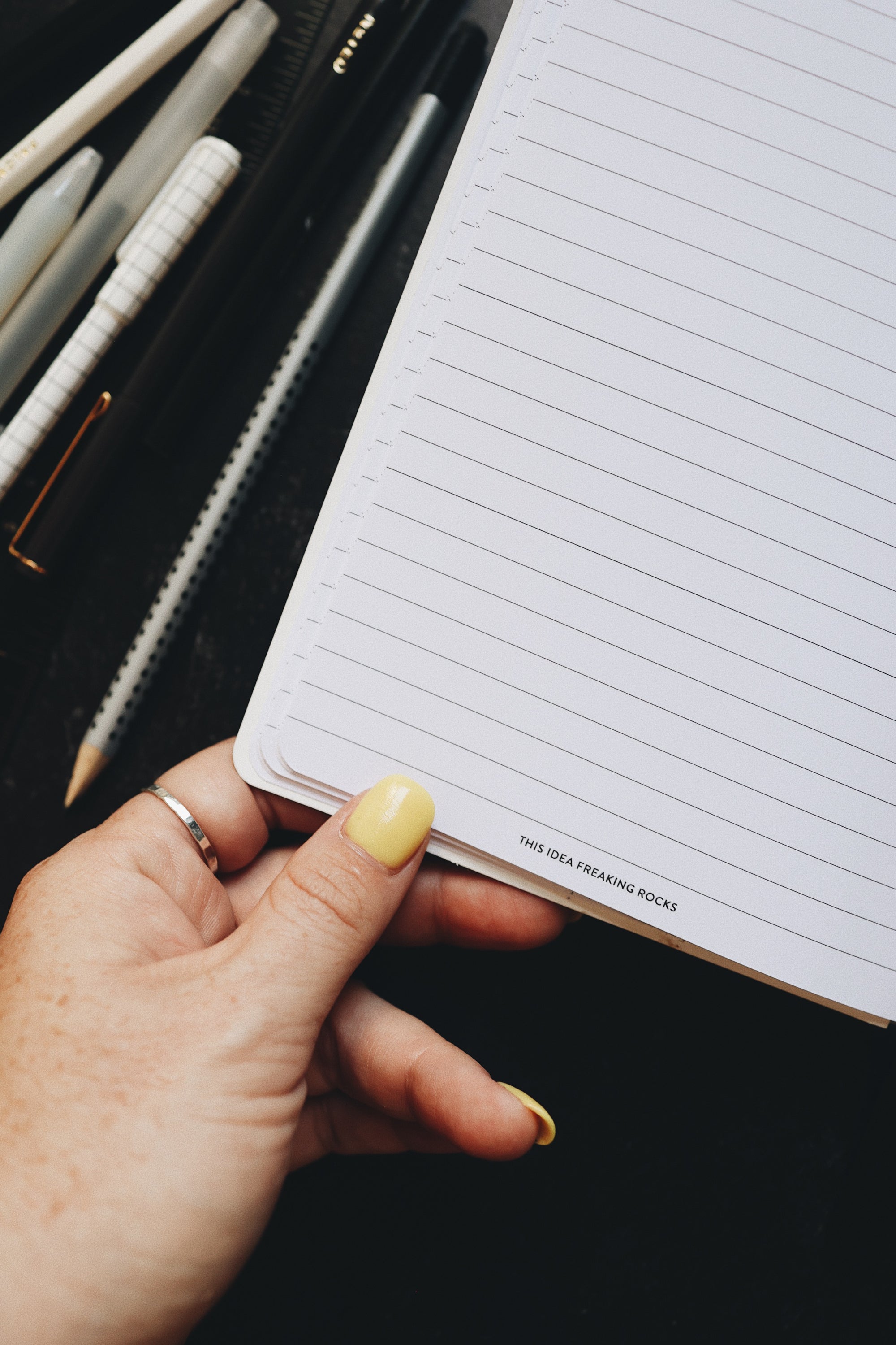 Thumb holding the creative planner open to the project page, artistic shot at an angle