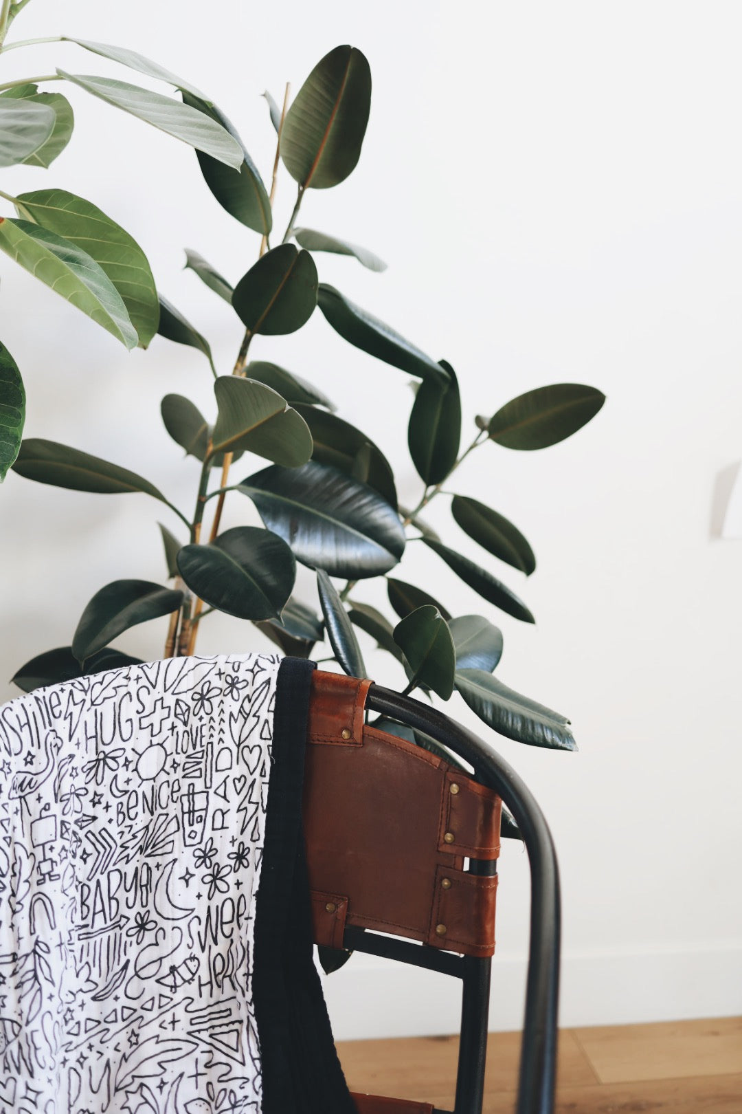 Artistic shot of the quilt draped over a chair with houseplants behind.