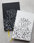 The mom & me journal partially on top of the dad & me journal on a desk