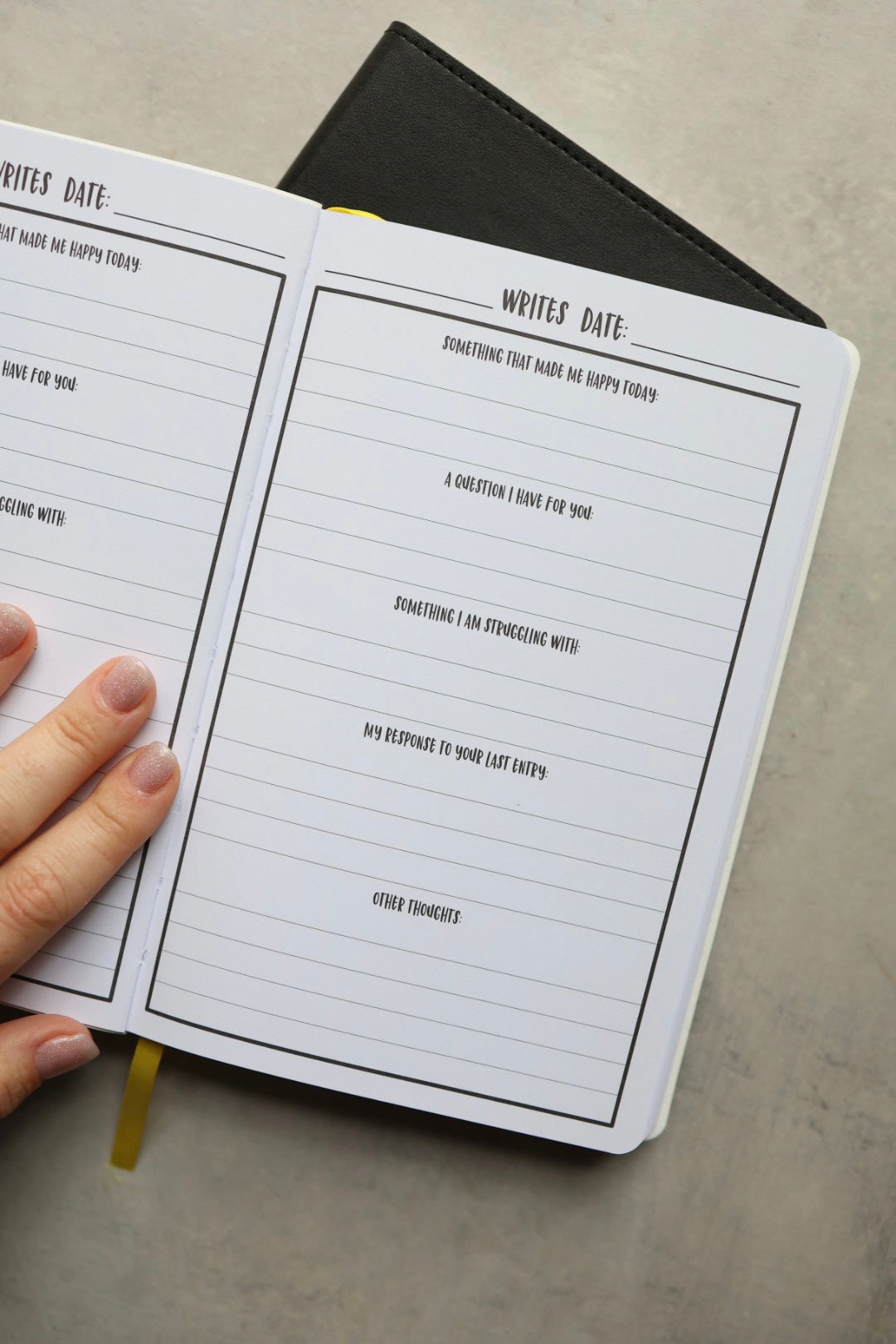 Inside page showing journal prompts and a hand holding the page flat