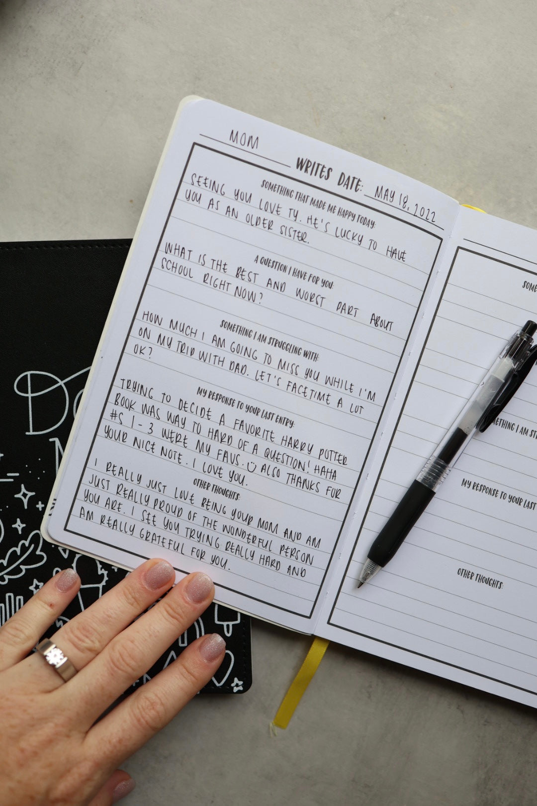Inside page of journal showing handwriting, a pen, and a hand.