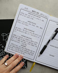 Inside page of journal showing handwriting, a pen, and a hand.
