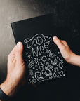 Two hands holding dad & me journal showing cover