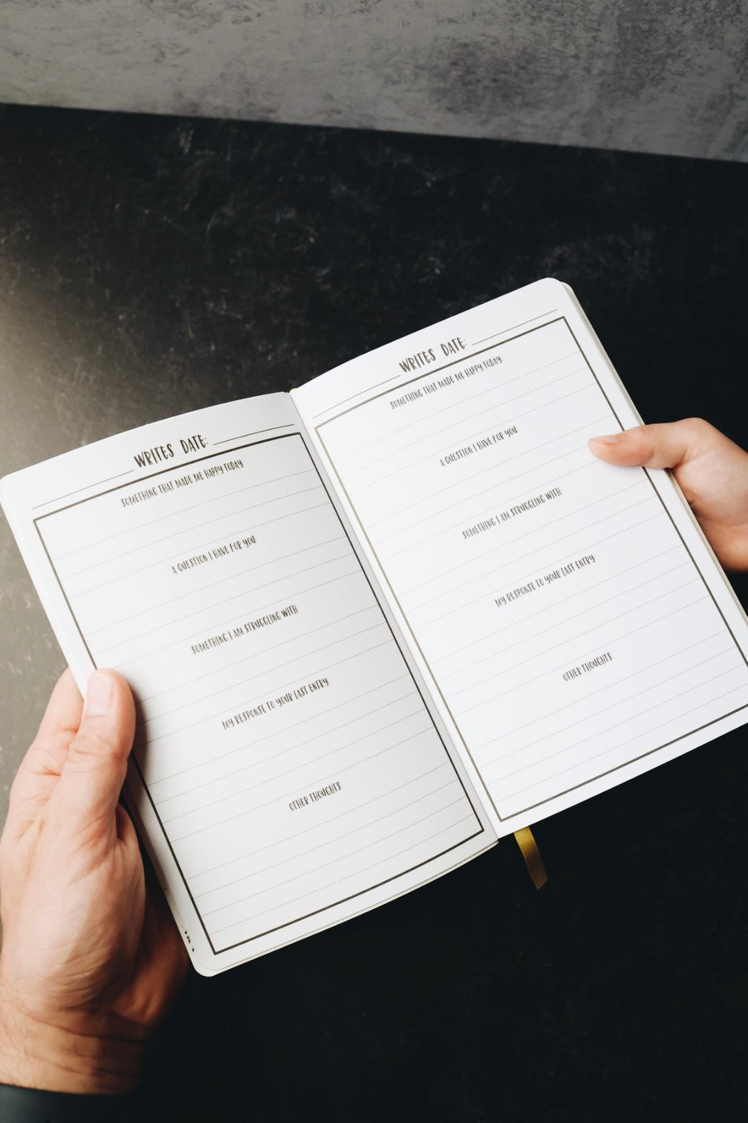 Two hands holding journal open to prompts page
