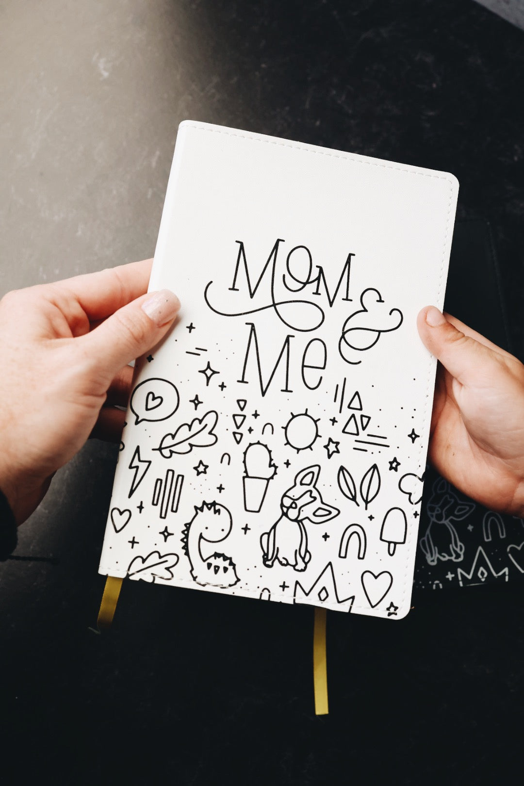 Two hands holding mom & me journal showing cover