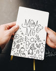 Two hands holding mom & me journal showing cover