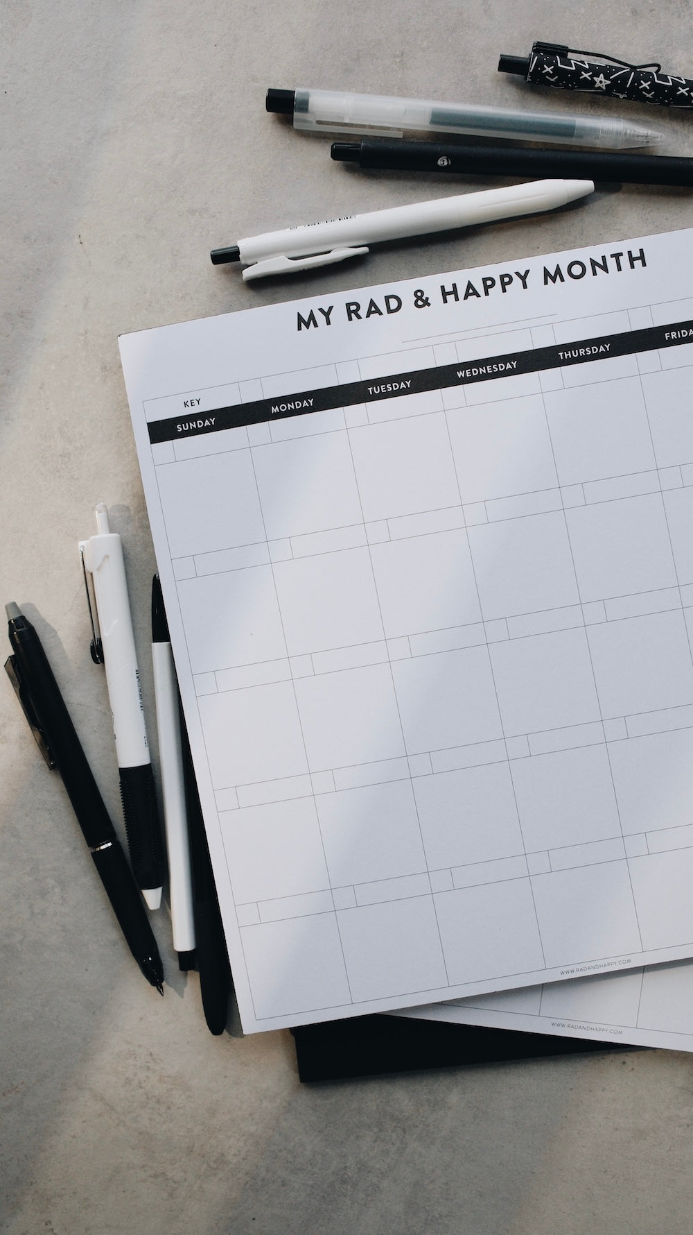 Month notepad with grid layout and pen on a gray surface