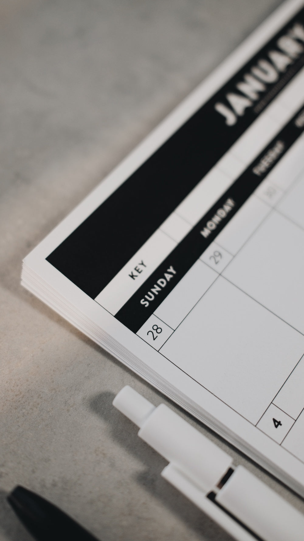 Image focused on the corner of a calendar with a pen on a gray surface surface