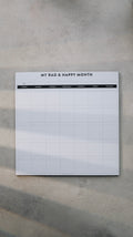Monthly notepad with grid layout on a gray surface