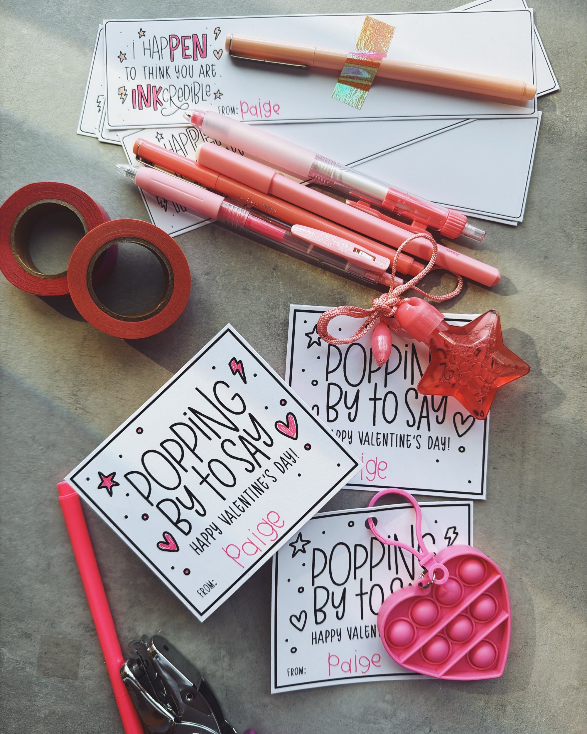 Valentine's Day cards, pens, and pop-it toys on a concrete surface