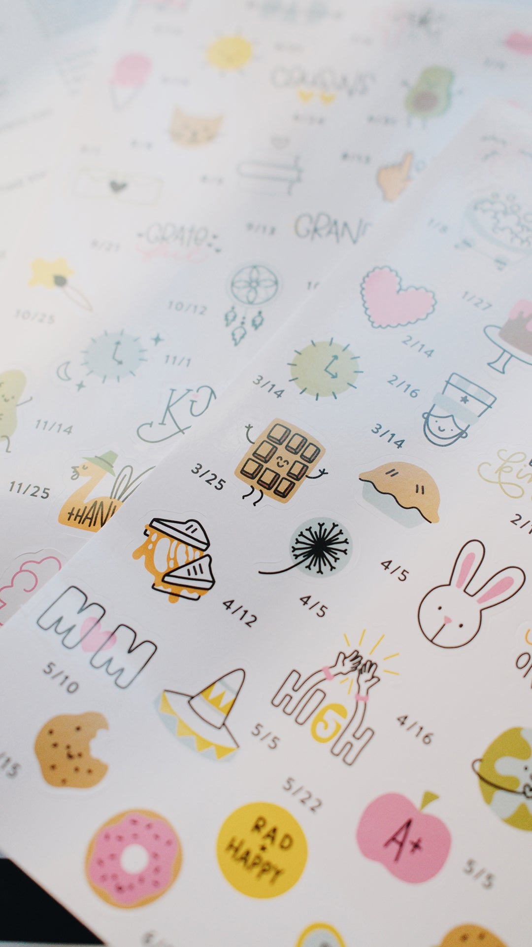 Artistic blurred shot of sheet of decorative stickers with various designs including cartoon characters, symbols, and text.