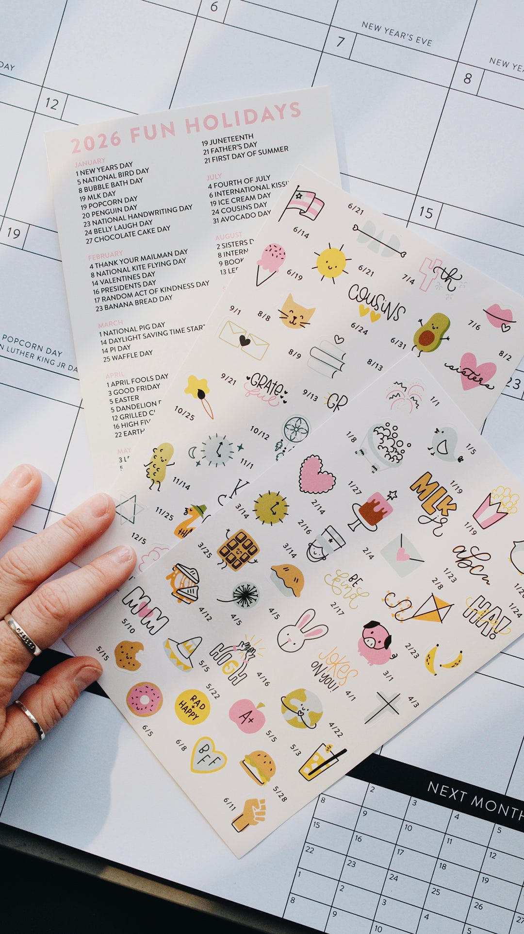 Sheet of decorative stickers with various designs held over a calendar.