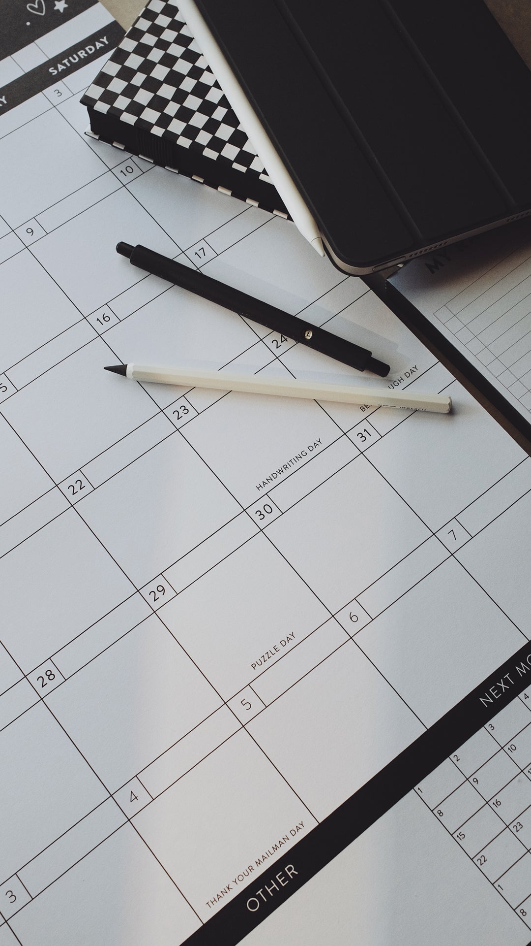 Pens and planners laying on top of a calendar page