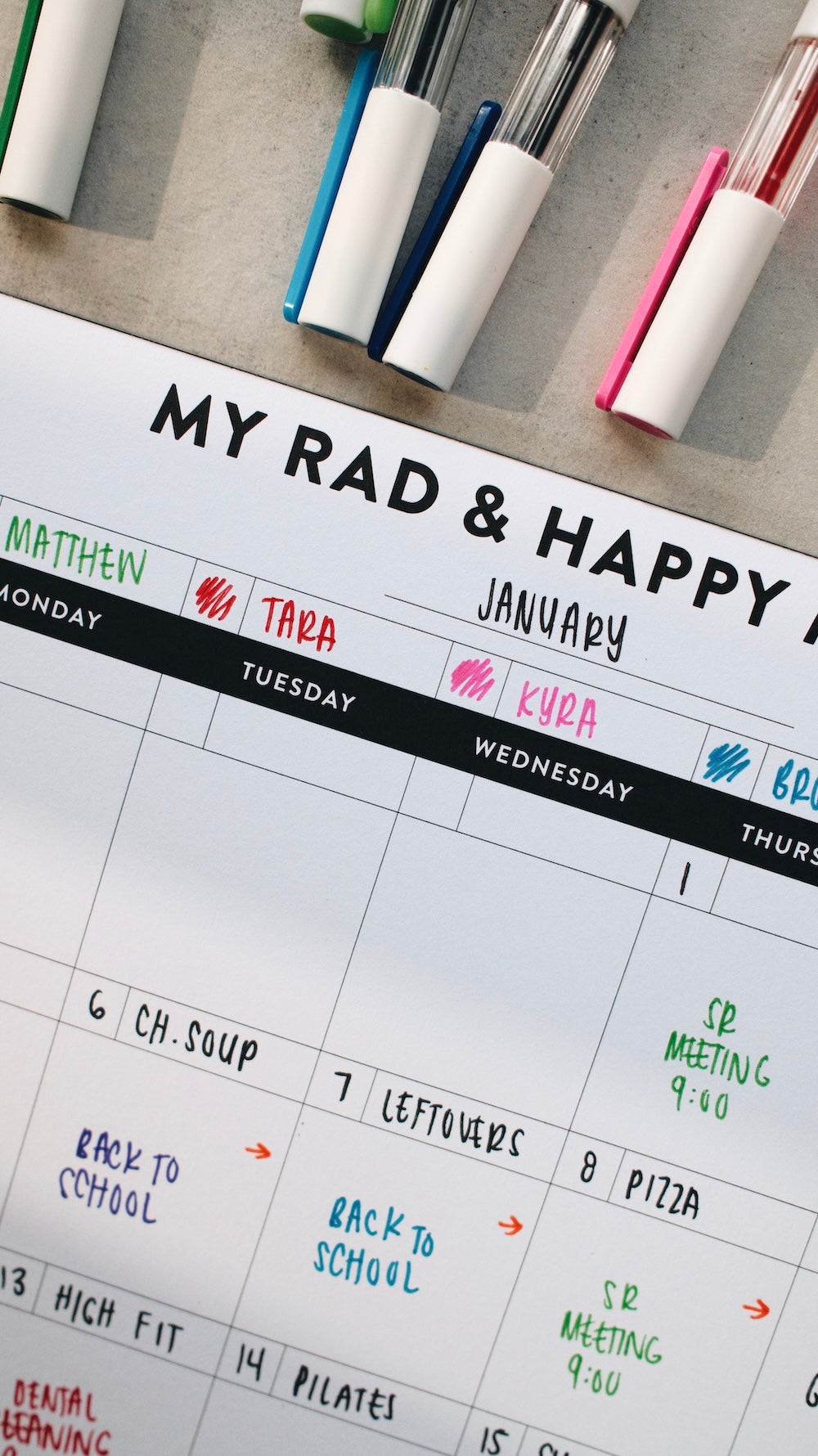 Month notepad with handwritten notes and markers on a desk