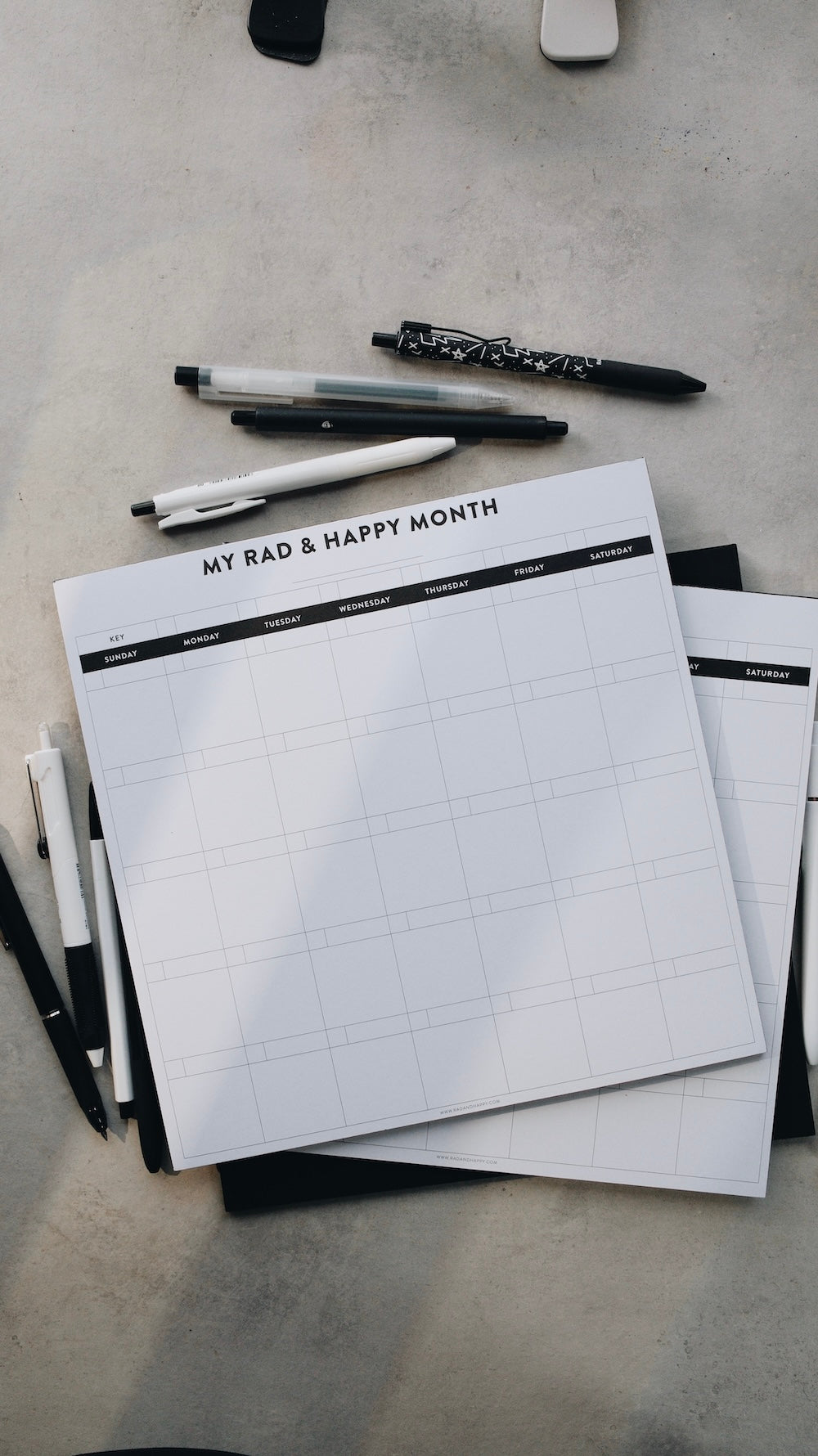 Stack of month notepads with grid layout and text on a gray surface