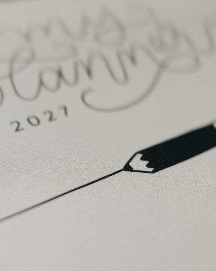 A close-up of a white textured planner page featuring elegant black cursive writing that reads 'my planning 2027' and a minimalist black pencil illustration.
