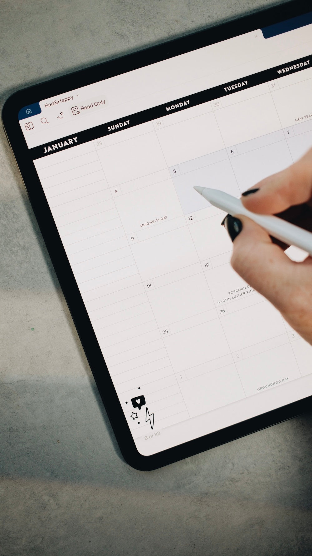 Person using a stylus to interact with a digital planner on a tablet.
