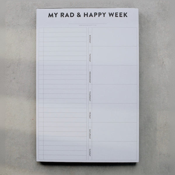 Weekly planner pad titled 'My Rad & Happy Week' on a gray surface