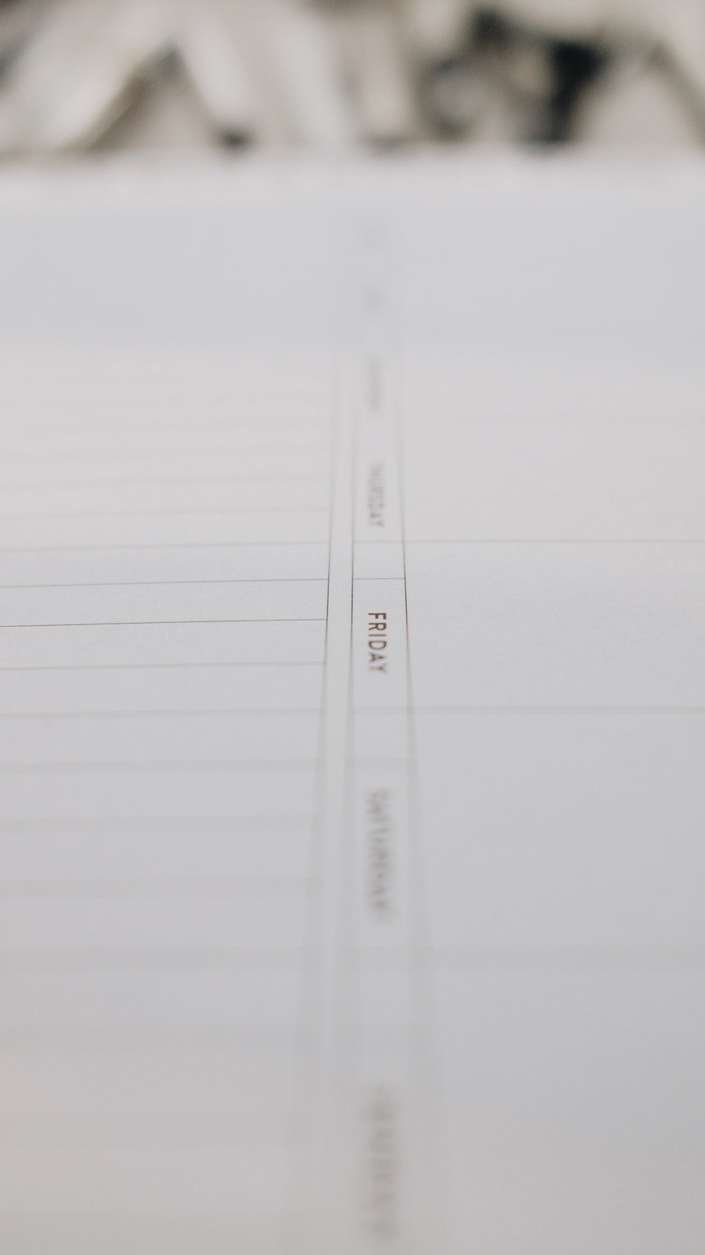 Close-up of a note pad focused on text 'FRIDAY' with blurred background.