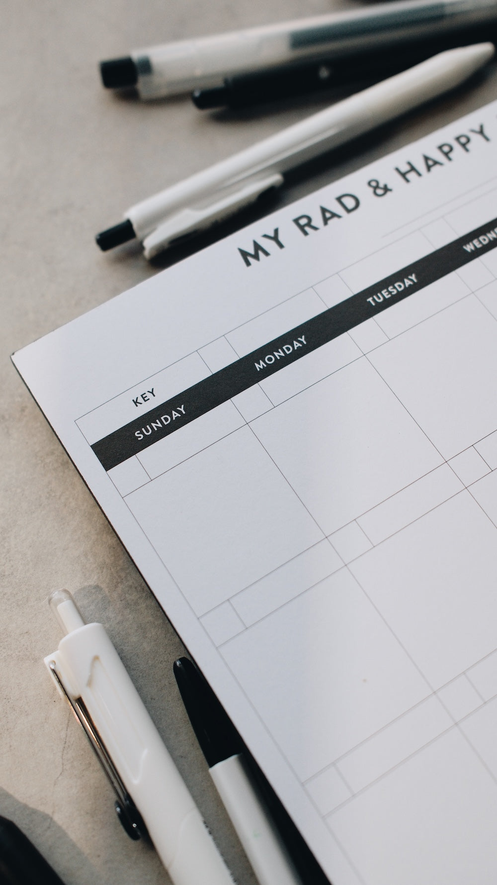 Month notepad with 'My Rad & Happy' branding and writing utensils on a light surface.