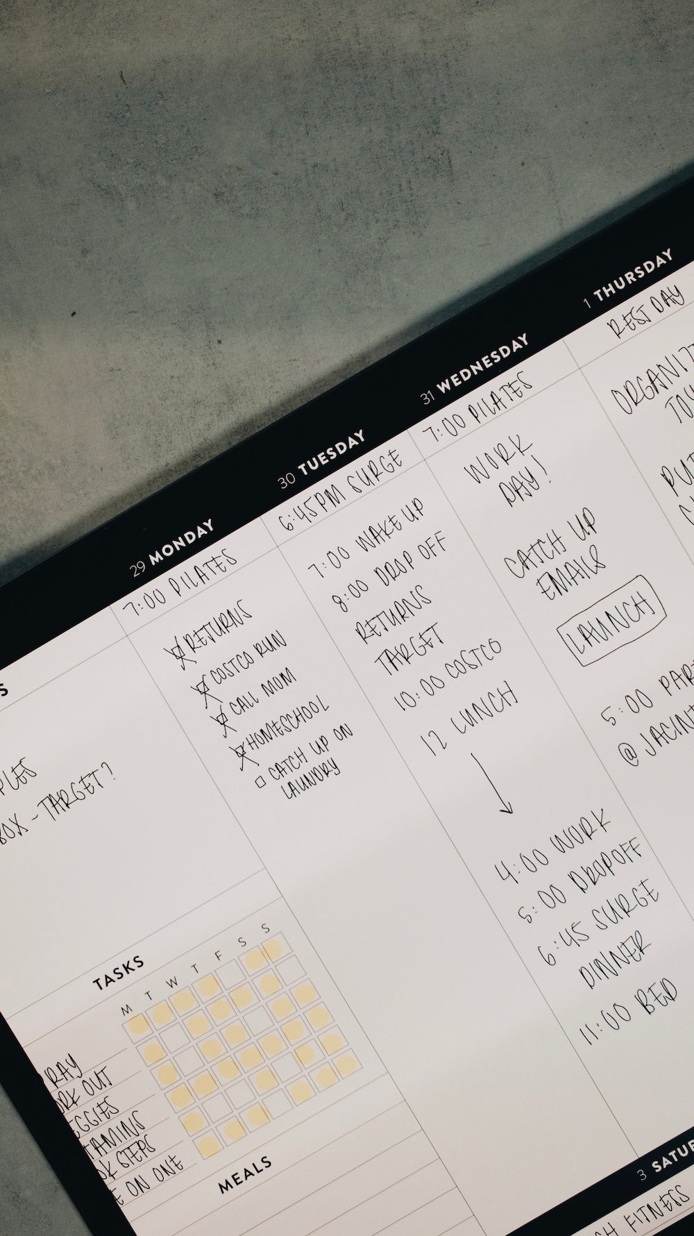 Close-up of a planner with handwritten notes and tasks on a gray surface