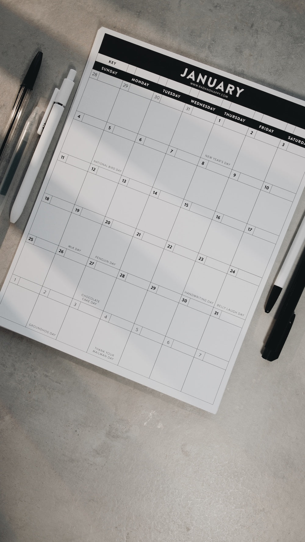 Calendar for January on a gray surface with pens and markers.