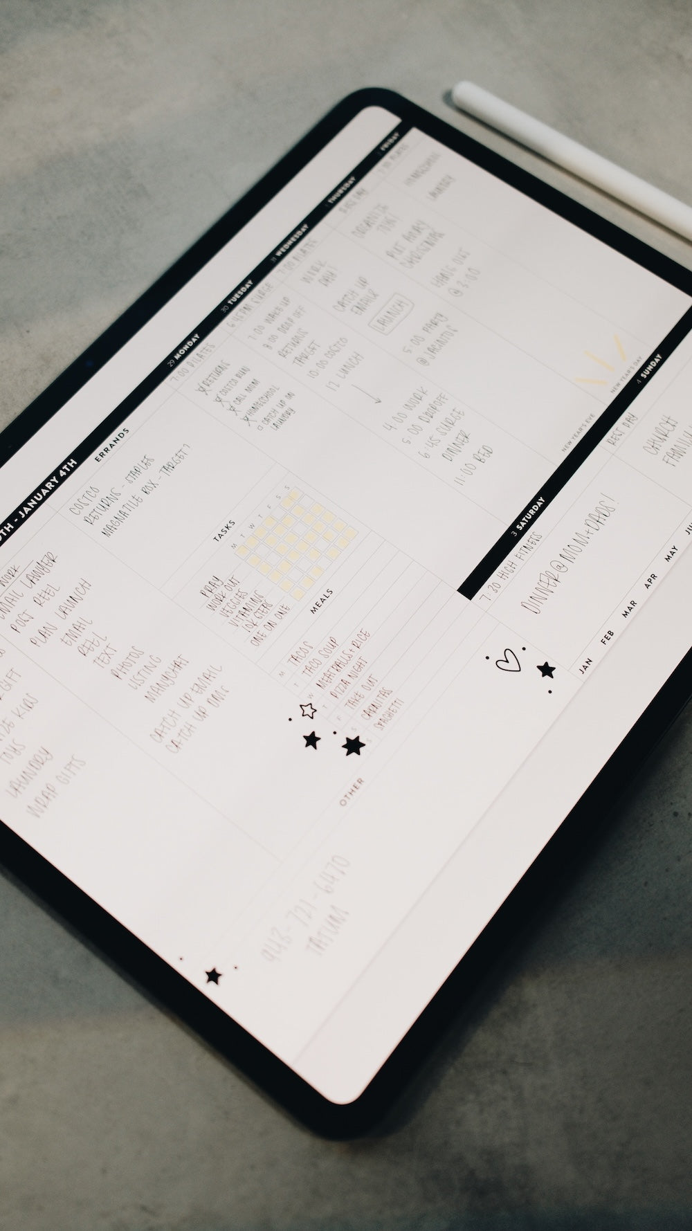 Tablet displaying a digital planner layout on a gray surface