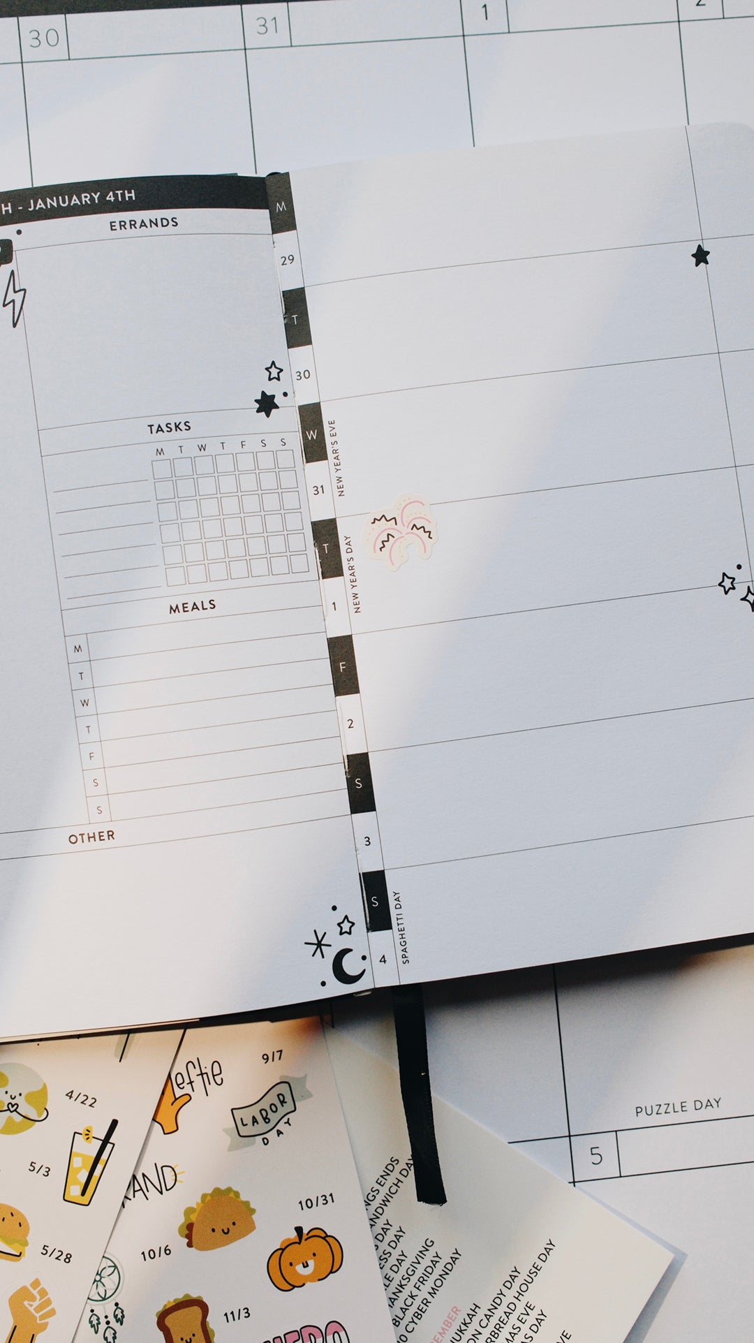 Planner with a fireworks sticker sitting on top of a calendar on a white surface