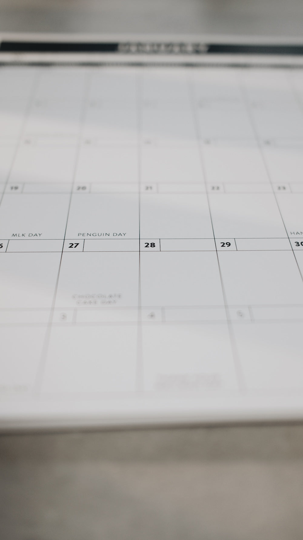 Calendar page blurred out and focused on a certain day with Penguin Day readable on a plain background