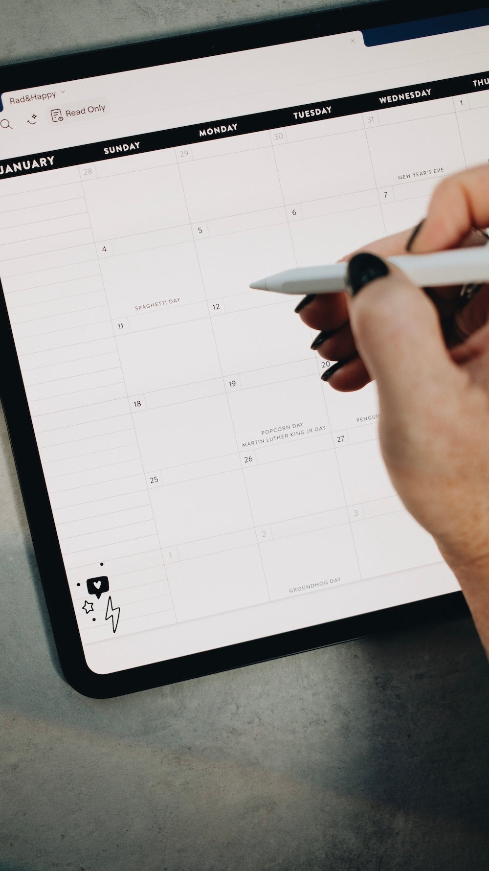 Person using a stylus on a digital planner displayed on a tablet.