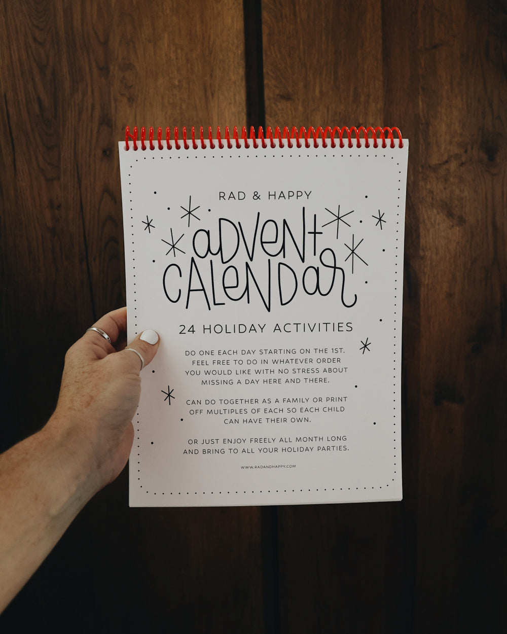 Person holding a 'Rad & Happy Advent Calendar' against a wooden background