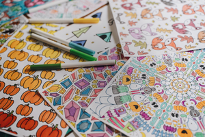 Coloring pages in a pile with pens and markers