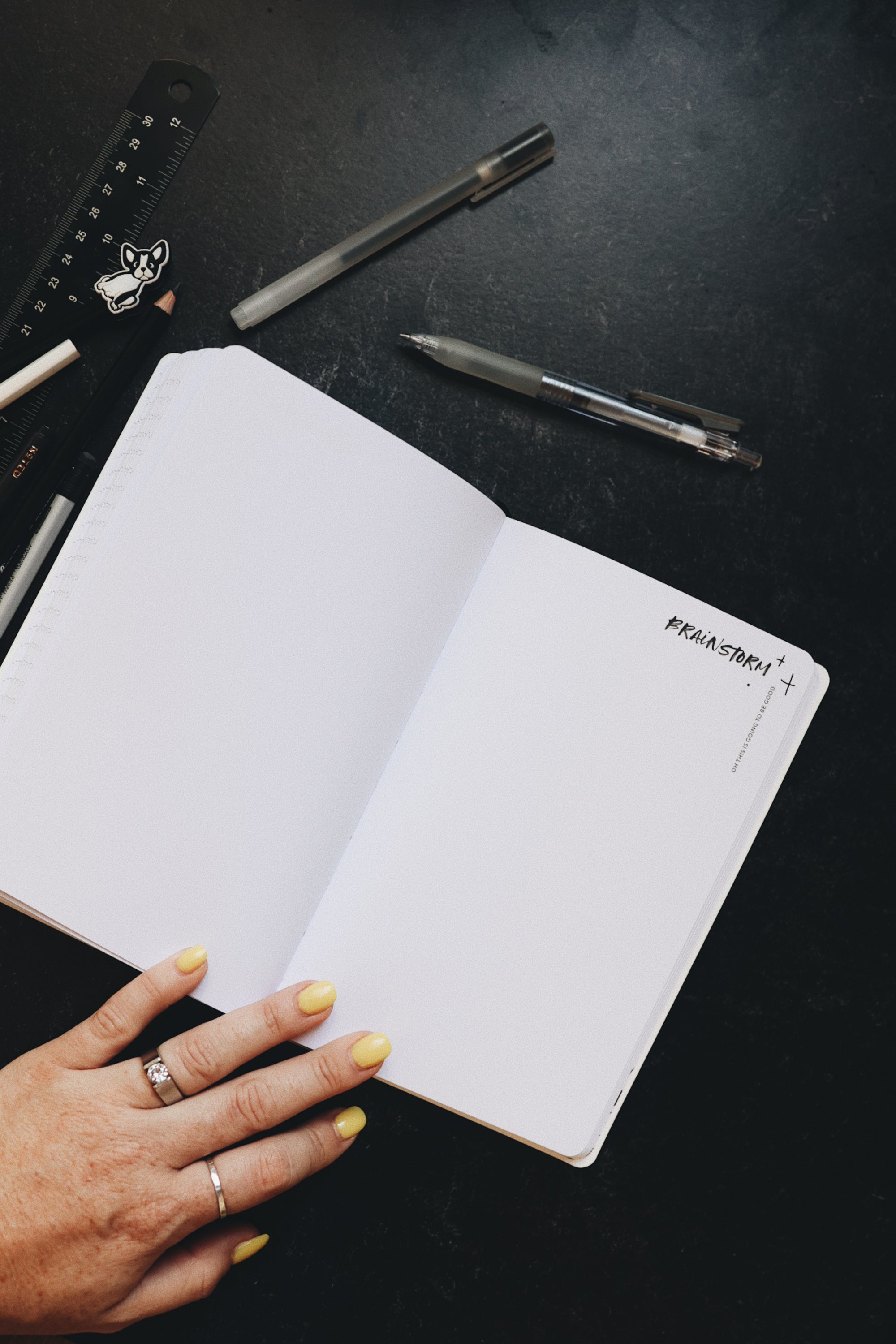 Creative planner opened to the brainstorm page, sitting alongside some pens and a ruler.