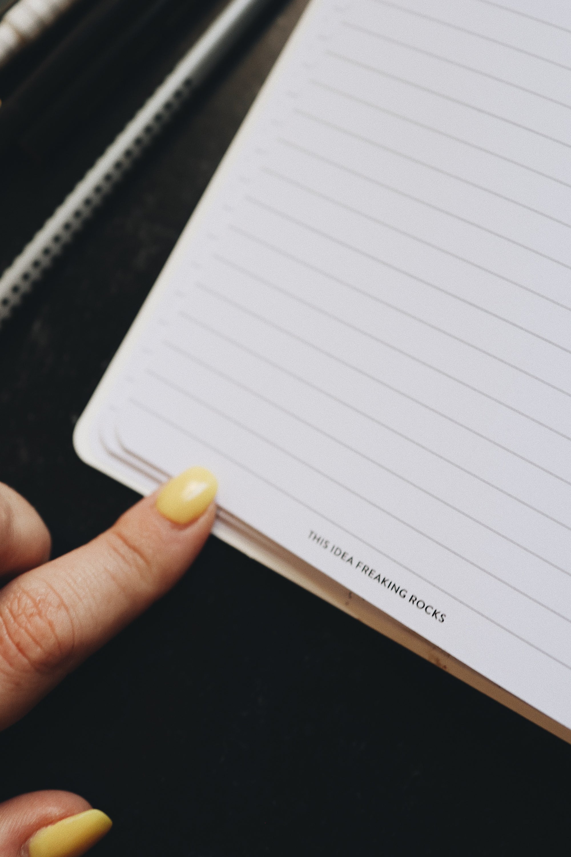 Artistic shot of a finger touching the open page of the planner that reads - this idea freaking rocks