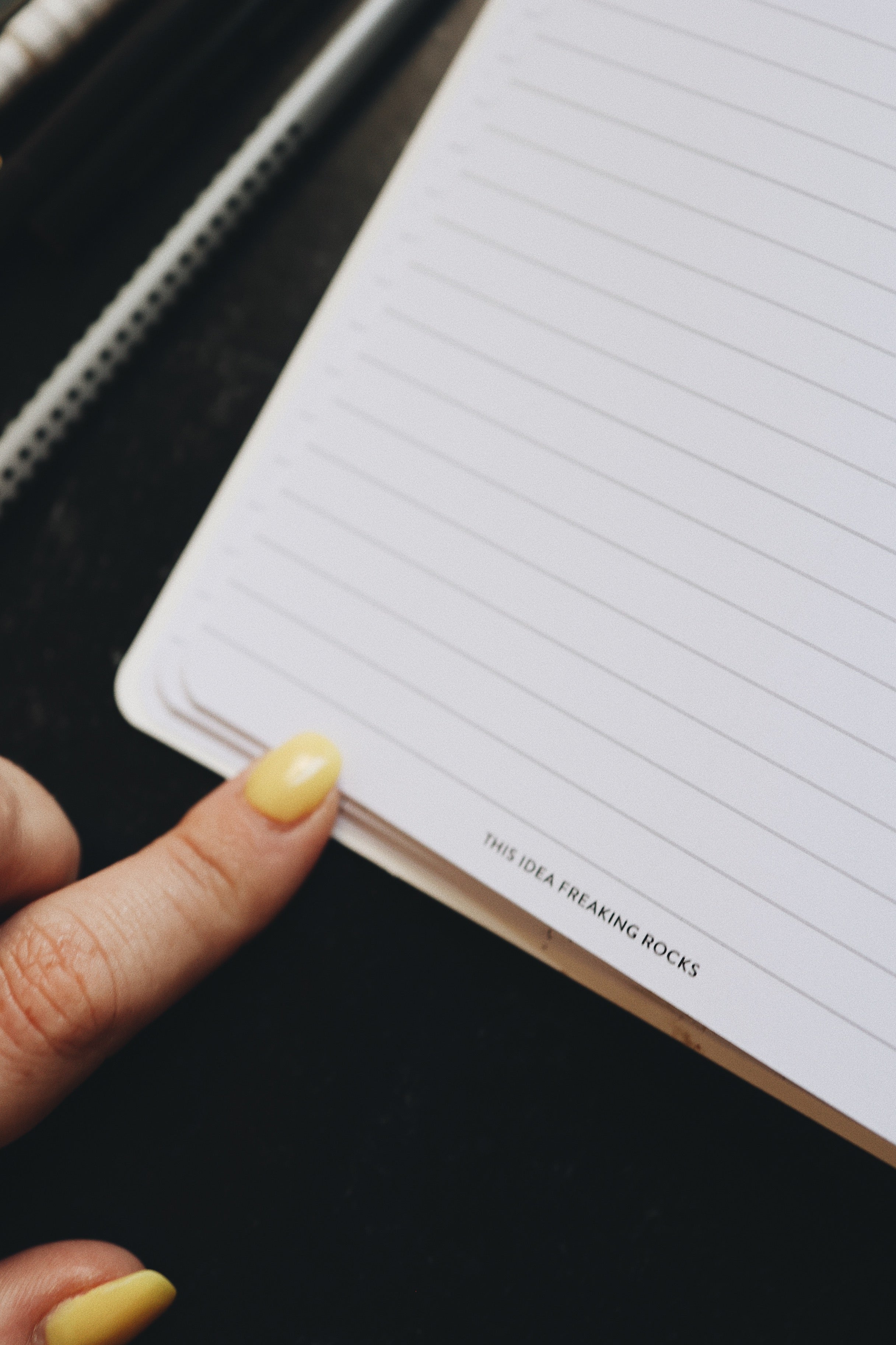 Artistic shot of a finger touching the open page of the planner that reads - this idea freaking rocks