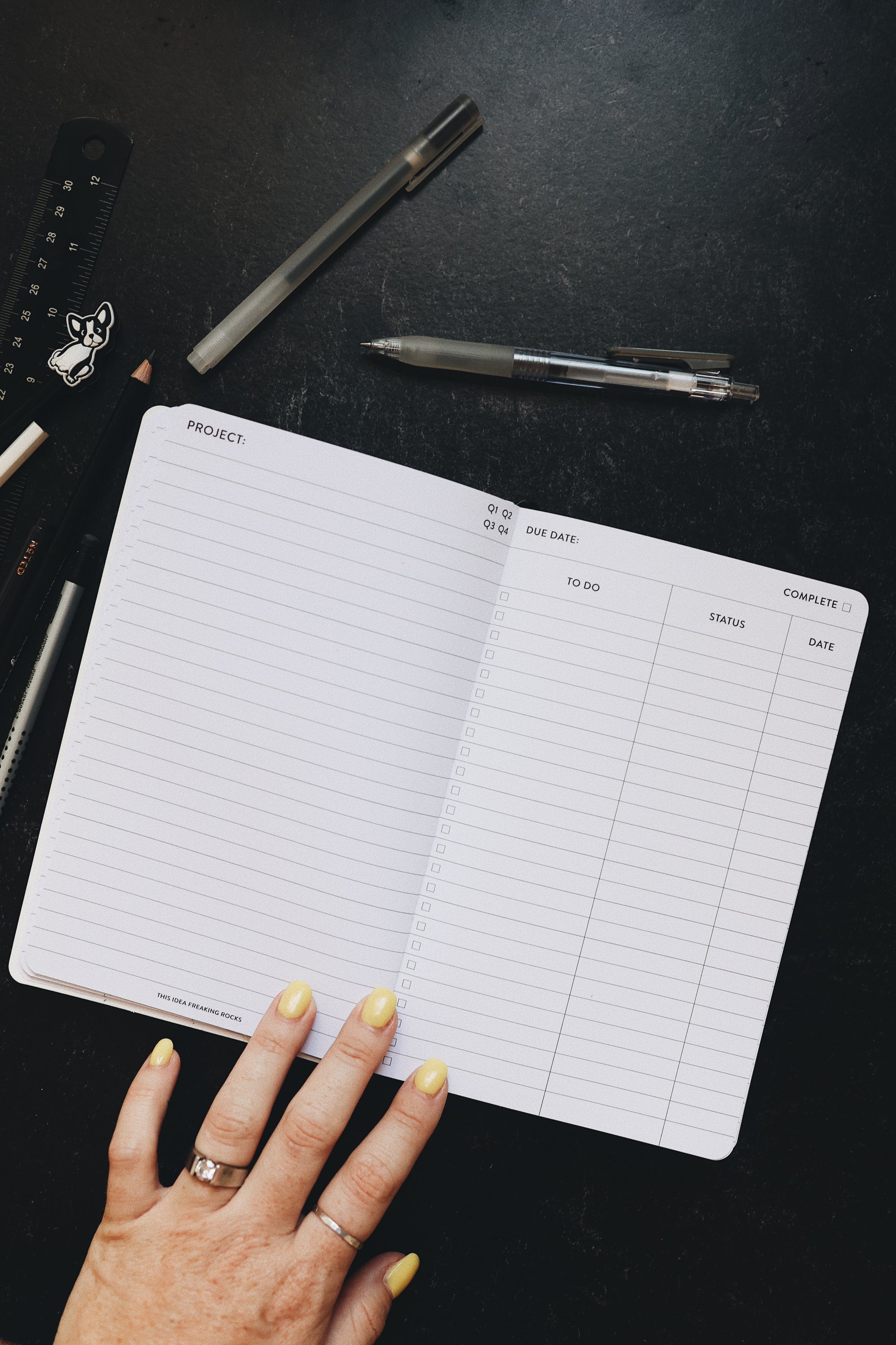Creative planner opened to the project page sitting alongside some pens and a ruler.