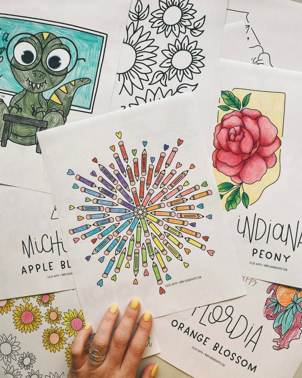 A hand on top of coloring pages laid out