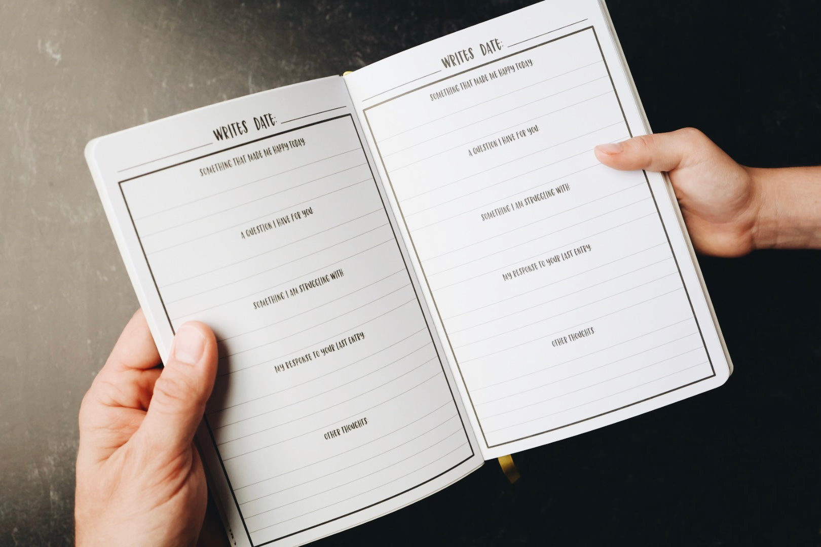 Two hands holding journal open to prompts page