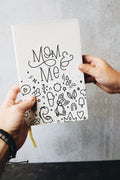 Two hands holding the mom & me journal