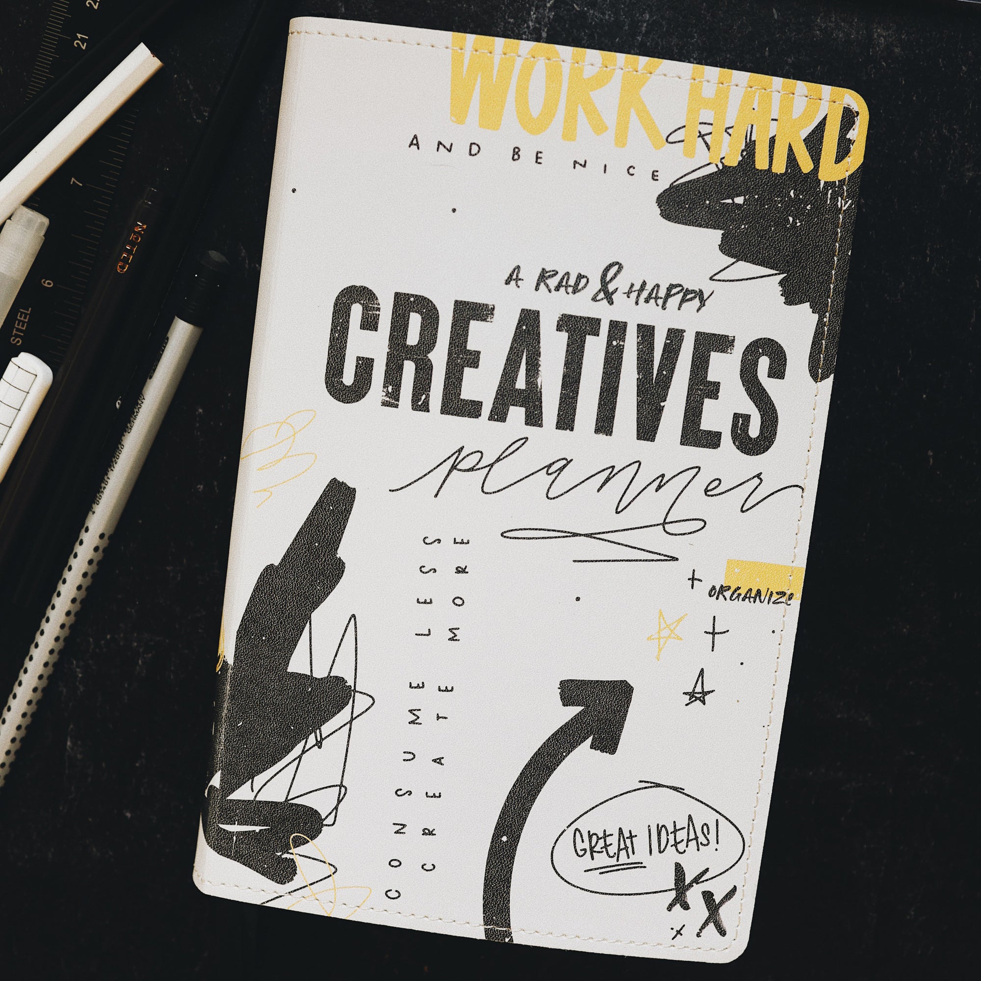 Creative planner sitting on desk along side pens and a ruler.